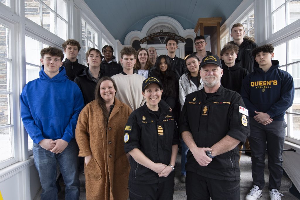 The 2025 Canadian Forces Base Halifax High School Navy Outreach Program students posing for a group photo with the Commander of Canadian Forces Base Halifax, Captain(N) Annick Fortin, the Base Chief, Chief Petty Officer 1st Class Troy Beazley, program coordinator Deirdre MacKenzie, and the students’ guide, Guy Godin, on the inside the main entry to the Naval Museum of Halifax. The students are wearing casual attire, and the military leaders are in black operational dress. / Les élèves participant au Programme de sensibilisation de la Marine dans les écoles secondaires 2025 posent pour une photo de groupe avec la commandante de la Base des Forces canadiennes Halifax, la capitaine de vaisseau Annick Fortin, le premier maître de la base, le premier maître de 1re classe Troy Beazley, la coordonnatrice du programme, Deirdre MacKenzie, et leur guide, Guy Godin, à l’intérieur de l’entrée principale du Musée naval d’Halifax. Les élèves sont en tenue décontractée et les militaires, en tenue opérationnelle noire.